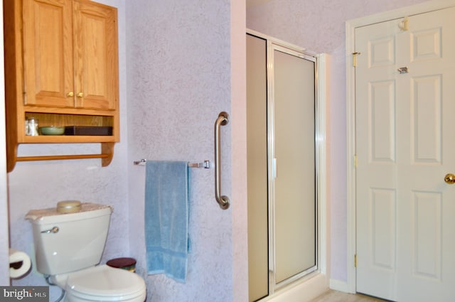 bathroom with toilet and a shower with door