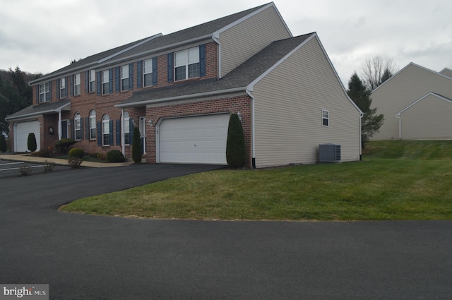 colonial house featuring a front yard, central AC unit, and a garage