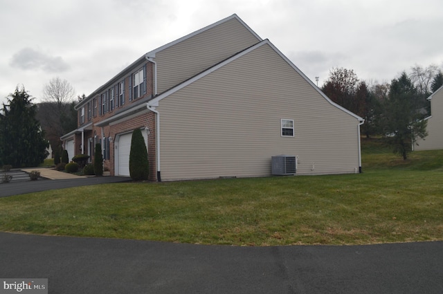 view of property exterior featuring central AC, a yard, and a garage