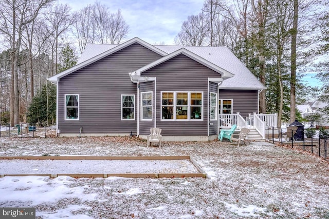 snow covered rear of property with a deck