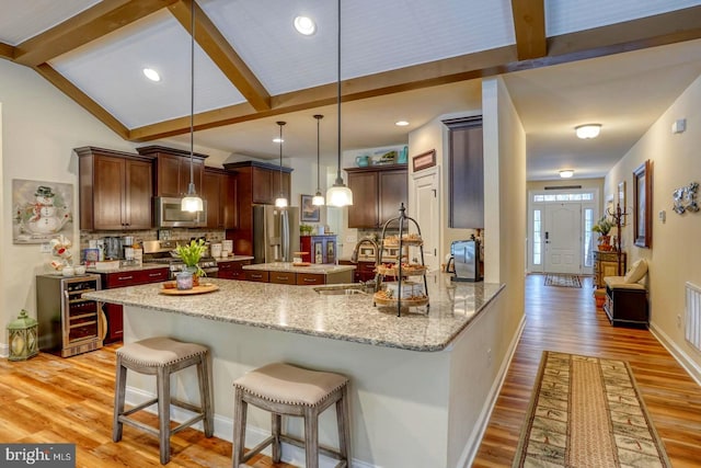 kitchen featuring sink, light stone counters, hanging light fixtures, appliances with stainless steel finishes, and kitchen peninsula