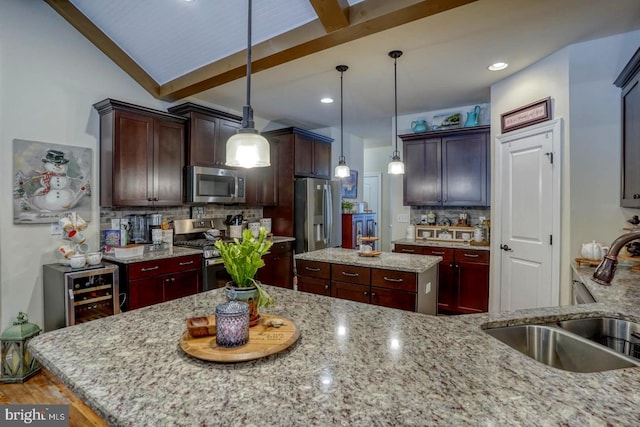 kitchen featuring sink, stainless steel appliances, light stone counters, a kitchen island, and decorative light fixtures