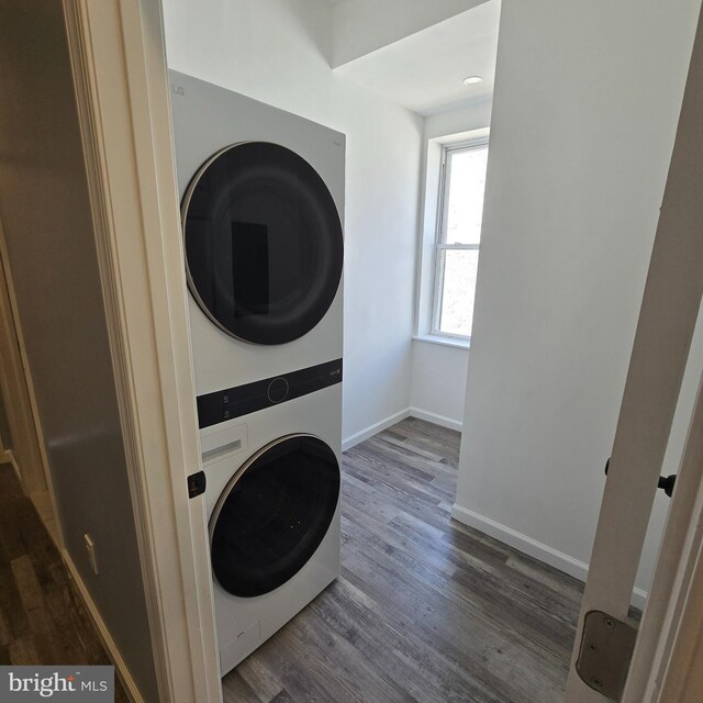 clothes washing area featuring dark hardwood / wood-style flooring and stacked washer and clothes dryer