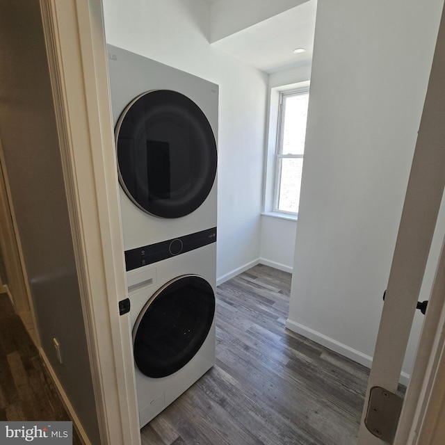 clothes washing area with stacked washing maching and dryer and dark wood-type flooring