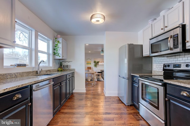 kitchen featuring white cabinets, stainless steel appliances, light stone countertops, and sink