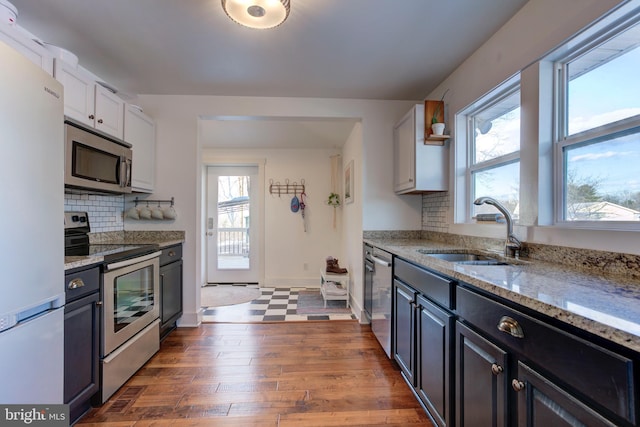 kitchen with light stone countertops, white cabinetry, sink, and stainless steel appliances