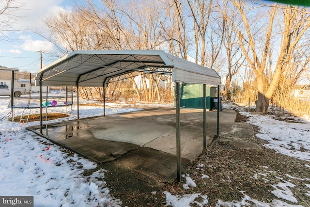 snow covered parking featuring a carport