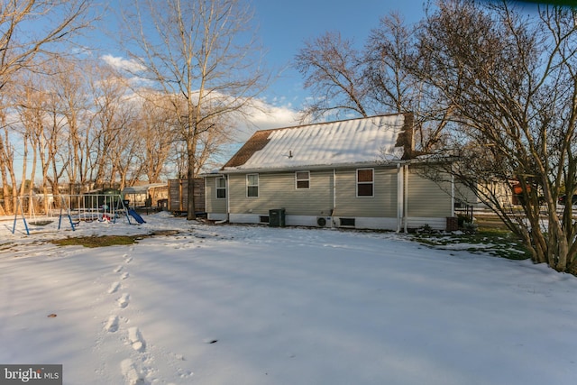 snow covered house featuring central AC unit and a playground