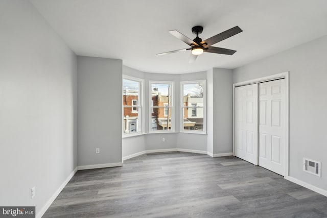 unfurnished bedroom with ceiling fan, a closet, and hardwood / wood-style flooring