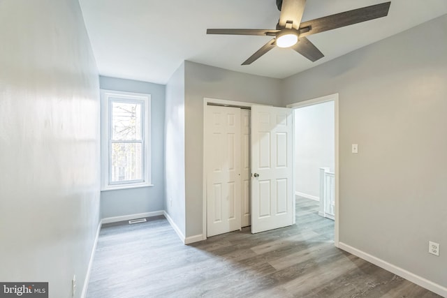 unfurnished bedroom featuring light wood-type flooring, ceiling fan, and a closet