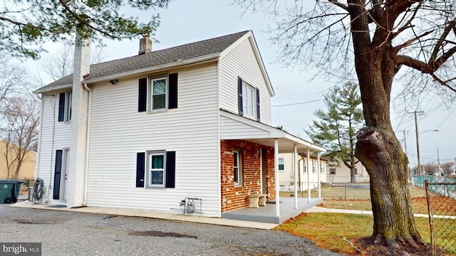 view of front of home featuring a shingled roof, a chimney, and fence