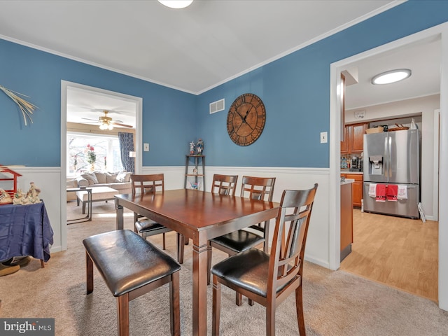 carpeted dining space with ceiling fan and ornamental molding