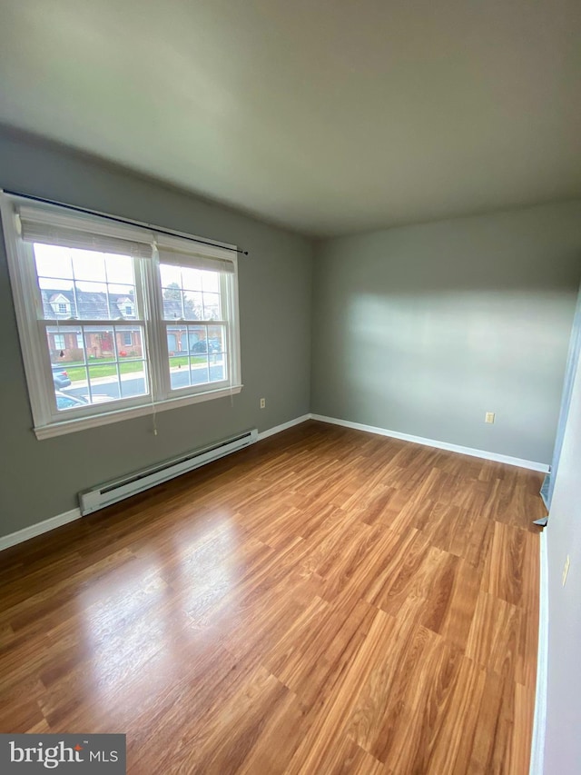 spare room with a baseboard radiator and light wood-type flooring