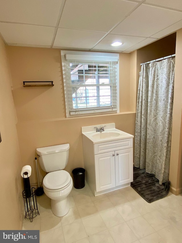 bathroom featuring a paneled ceiling, vanity, curtained shower, and toilet