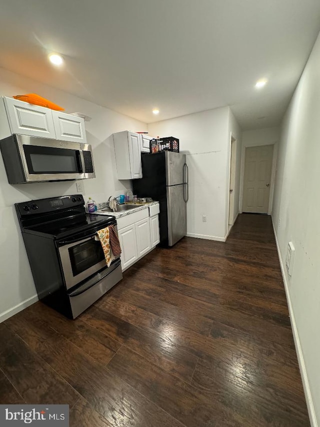 kitchen with stainless steel appliances, white cabinetry, dark wood-type flooring, and sink