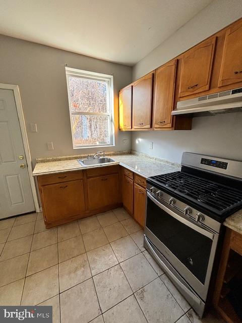 kitchen featuring sink, stainless steel stove, and light tile patterned floors