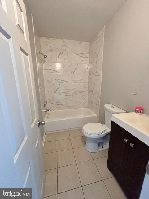 full bathroom with tile patterned floors, vanity, tiled shower / bath combo, and toilet