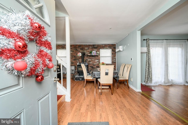 dining area featuring hardwood / wood-style floors, a wood stove, and brick wall