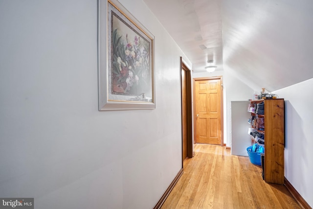 corridor with light hardwood / wood-style flooring and lofted ceiling