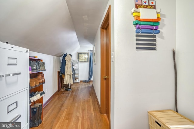 hallway with light hardwood / wood-style flooring and vaulted ceiling