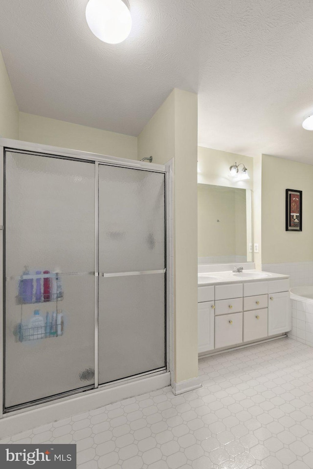 bathroom featuring a textured ceiling, separate shower and tub, and vanity