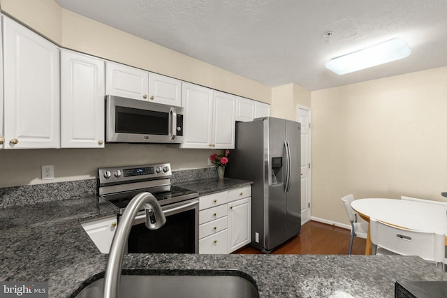 kitchen with a textured ceiling, dark hardwood / wood-style floors, stainless steel appliances, white cabinets, and sink