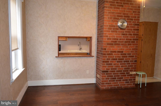 unfurnished living room featuring dark hardwood / wood-style flooring, ornamental molding, and sink