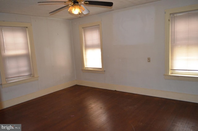 empty room with ceiling fan and dark hardwood / wood-style flooring