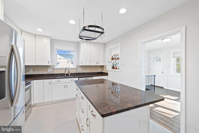 kitchen featuring appliances with stainless steel finishes, a sink, a center island, and white cabinets