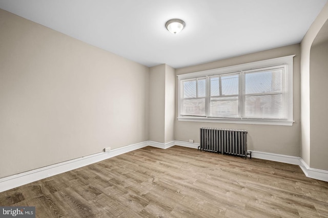 spare room featuring radiator heating unit and light hardwood / wood-style floors