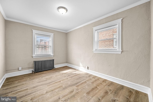 unfurnished room with ornamental molding, light wood-type flooring, and radiator heating unit