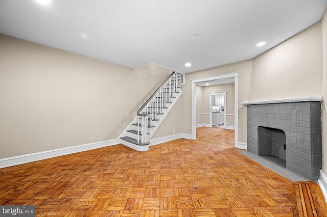 unfurnished living room with a brick fireplace and light parquet floors