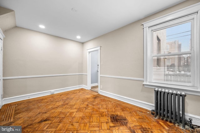 unfurnished room featuring parquet flooring, vaulted ceiling, and radiator