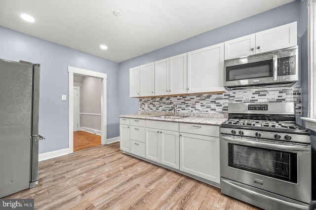 kitchen featuring light hardwood / wood-style flooring, stainless steel appliances, backsplash, white cabinetry, and sink