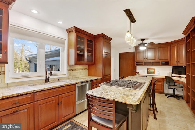 kitchen with pendant lighting, sink, ceiling fan, a kitchen island, and a breakfast bar area