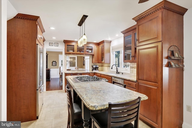 kitchen featuring sink, a center island, a kitchen breakfast bar, decorative light fixtures, and appliances with stainless steel finishes