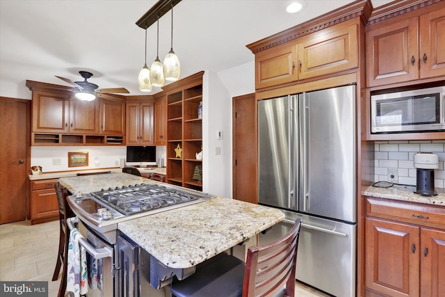 kitchen with a center island, a kitchen breakfast bar, ceiling fan, light stone countertops, and premium appliances