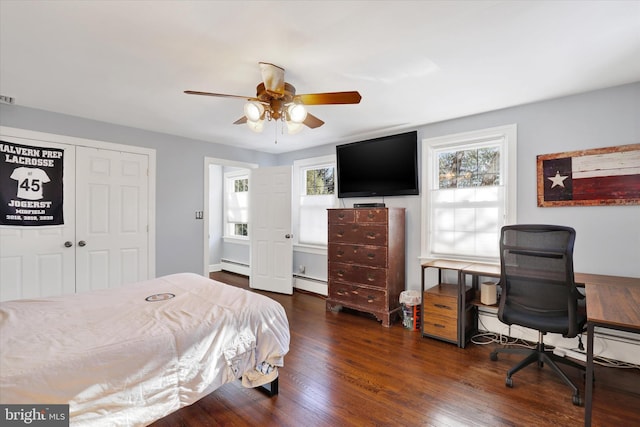 bedroom featuring ceiling fan, dark hardwood / wood-style floors, baseboard heating, and a closet