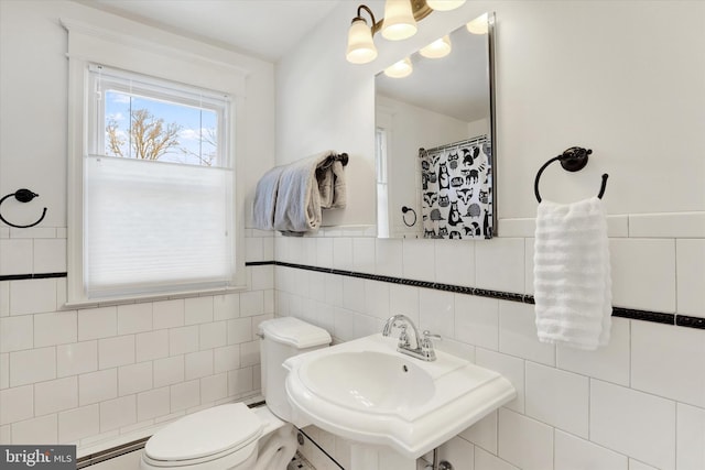 bathroom featuring toilet, sink, and tile walls