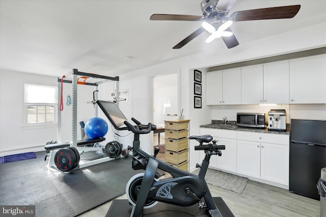 workout area with ceiling fan, sink, and light wood-type flooring