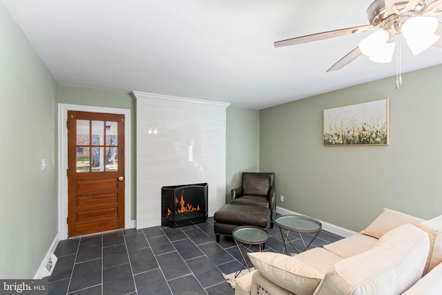 sitting room with ceiling fan and a large fireplace