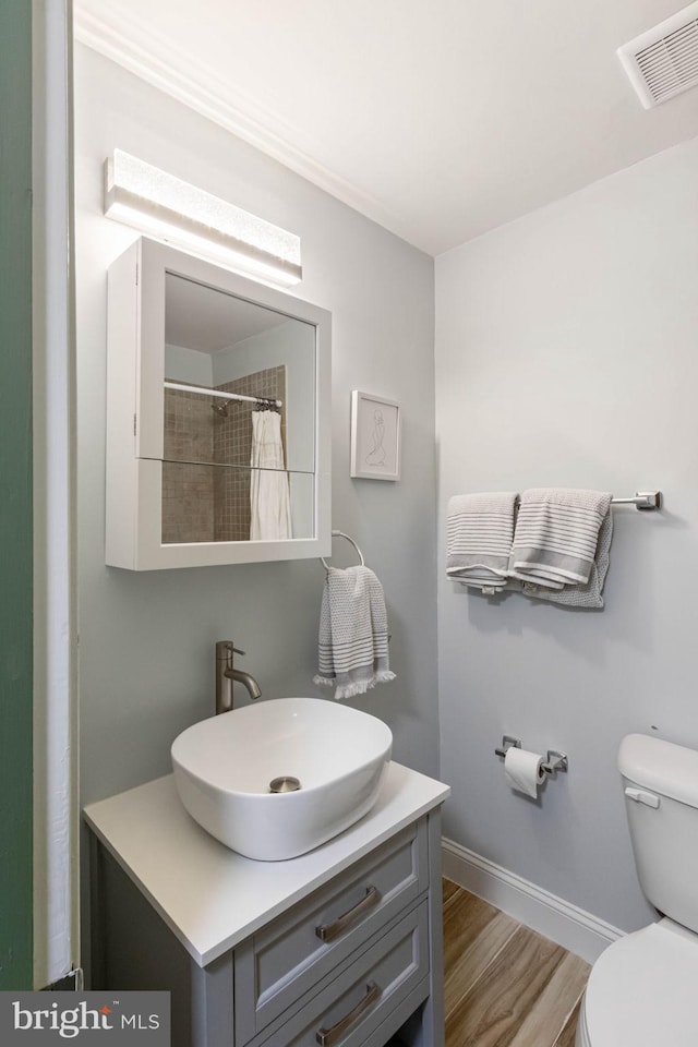 bathroom with curtained shower, vanity, wood-type flooring, and toilet