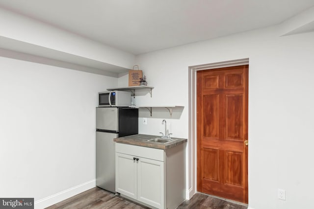 kitchen with stainless steel fridge, dark hardwood / wood-style flooring, white cabinetry, and sink