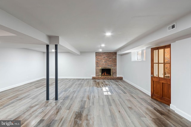 basement with a fireplace and light hardwood / wood-style flooring