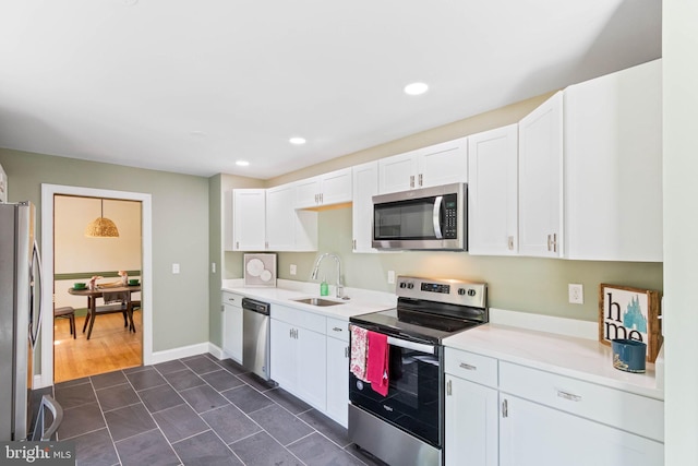 kitchen featuring stainless steel appliances, white cabinetry, hanging light fixtures, and sink