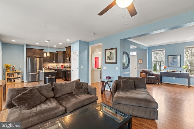 living room featuring ceiling fan, light hardwood / wood-style flooring, and ornamental molding