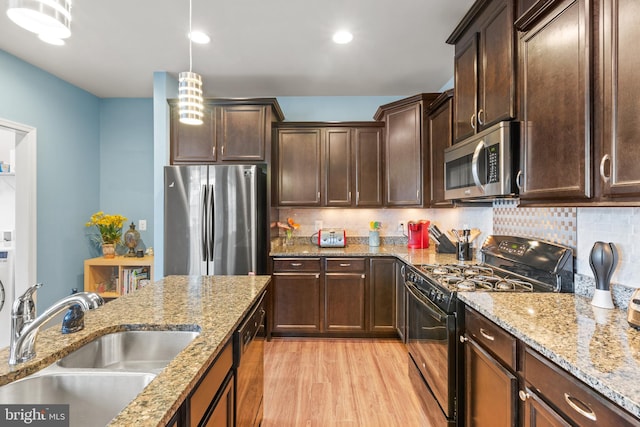 kitchen featuring sink, tasteful backsplash, light hardwood / wood-style floors, decorative light fixtures, and black appliances