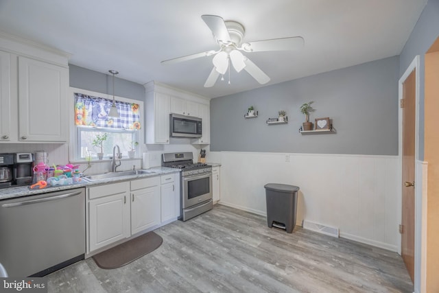 kitchen featuring white cabinets, appliances with stainless steel finishes, decorative light fixtures, sink, and ceiling fan