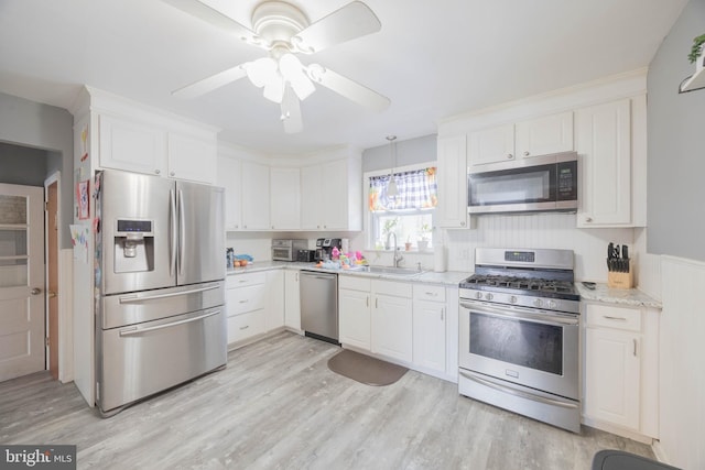 kitchen with white cabinets, appliances with stainless steel finishes, sink, ceiling fan, and light stone counters