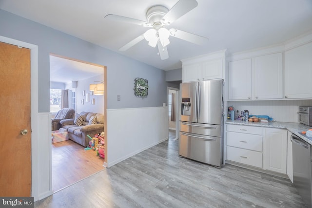 kitchen featuring ceiling fan, white cabinetry, light wood-type flooring, appliances with stainless steel finishes, and light stone counters